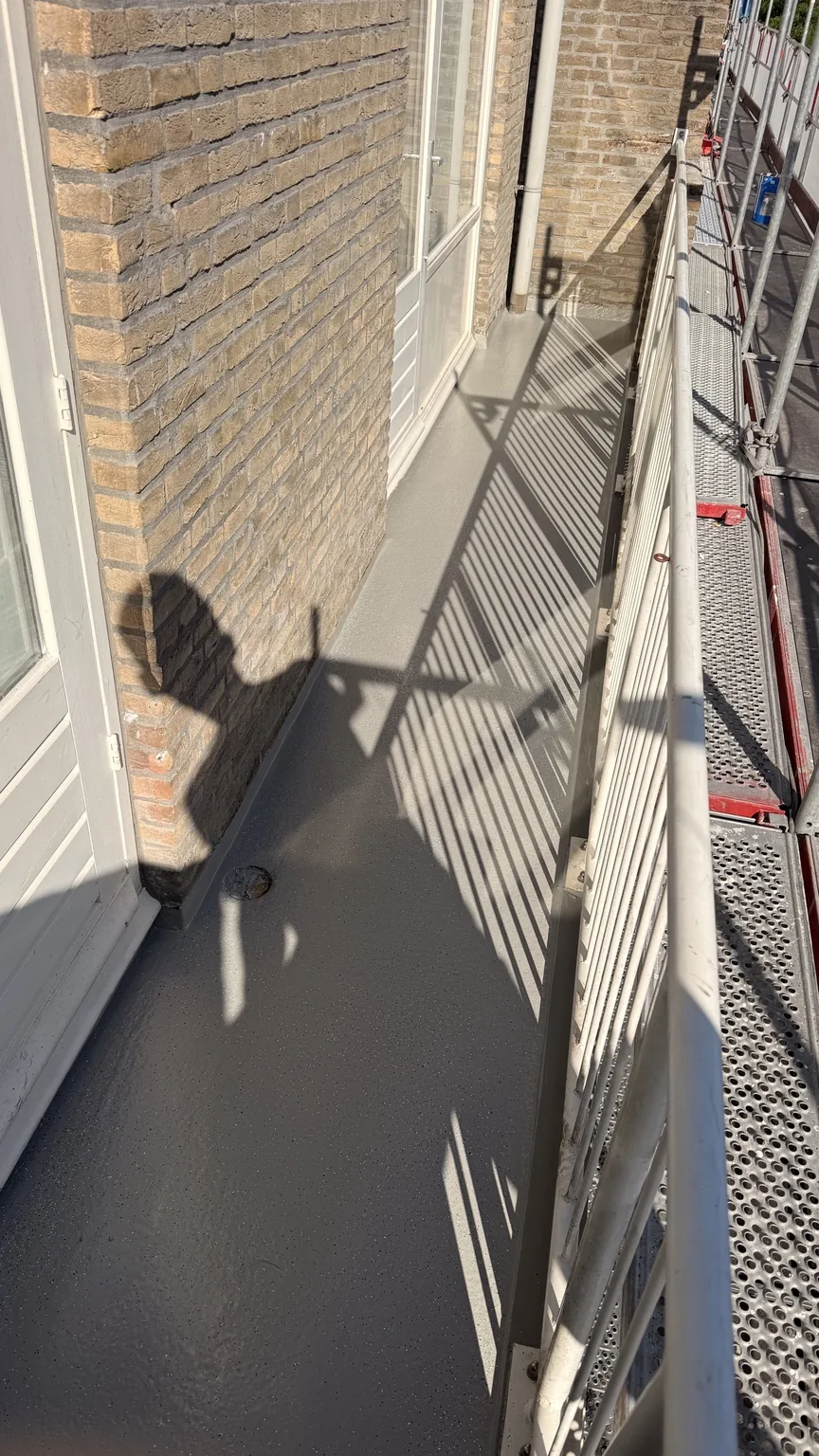 Gecoate balkonvloer in de zon met schaduw van de balustrade